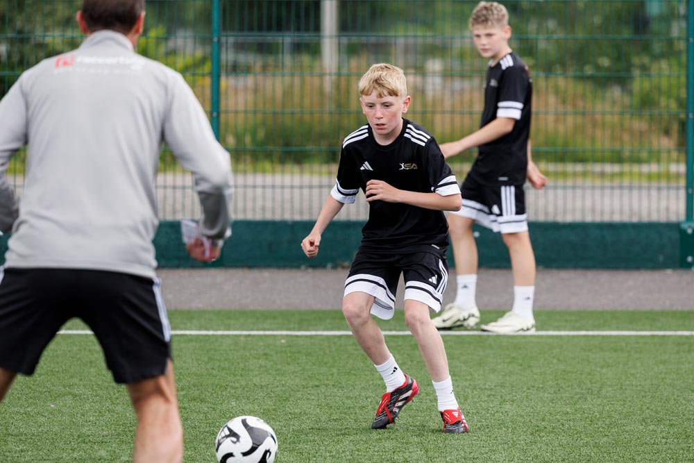 Young boy running towards a football during a practice session
